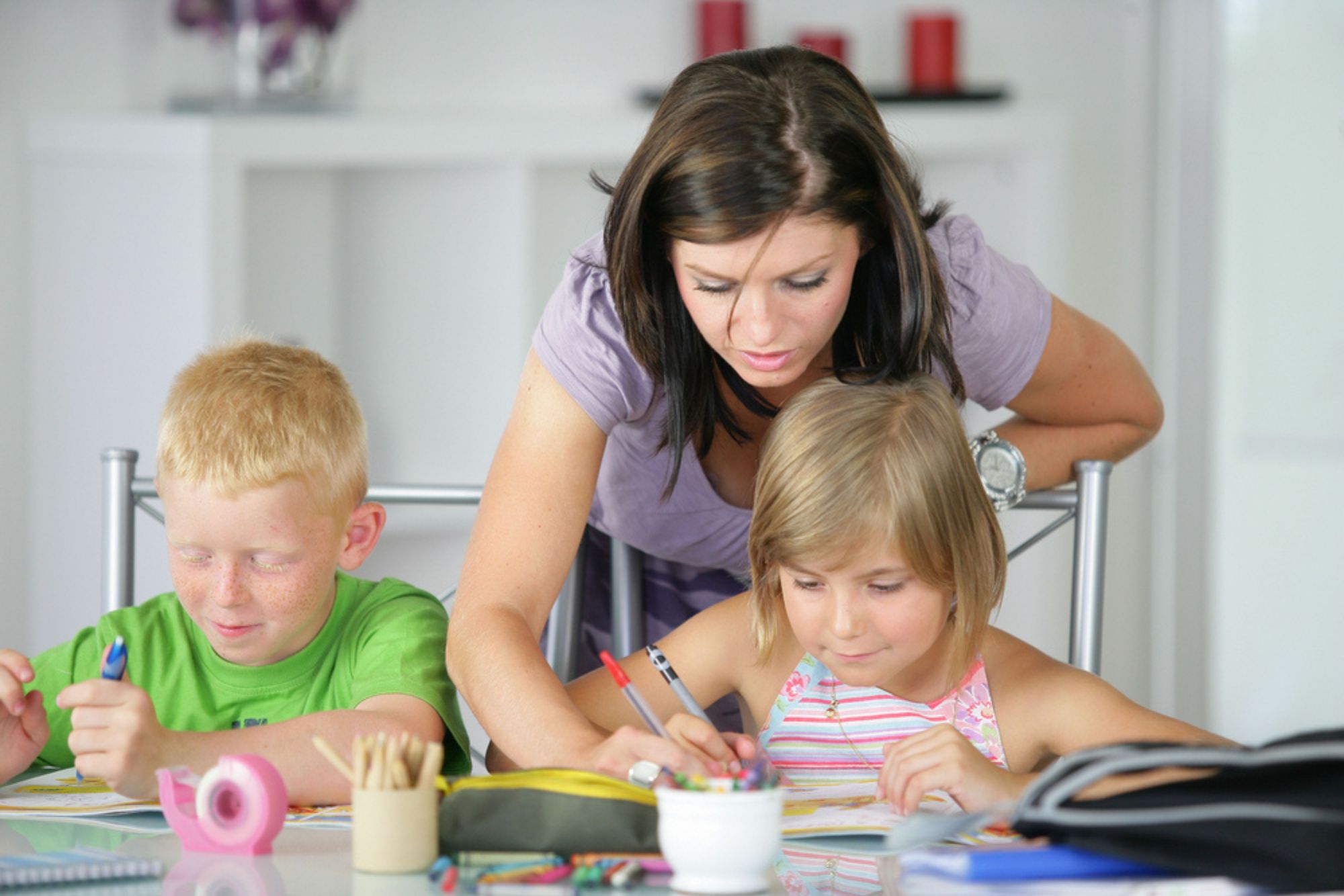 Une aide périscolaire encadrant deux enfants lors d'activités éducatives à domicile, symbolisant une organisation périscolaire adaptée pour simplifier le quotidien des parents.